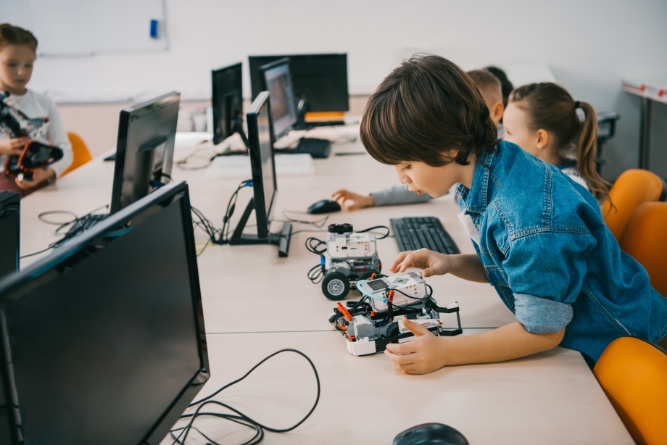 Boy playing with a robot in a computer classroom