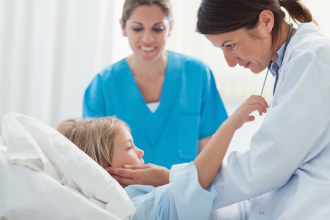 Female doctor and nurse caring for a child in hospital